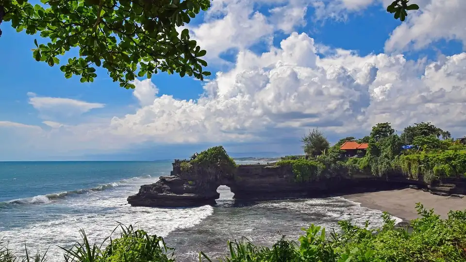 The stone arch and the black sand cove seen from the clifftop gardens