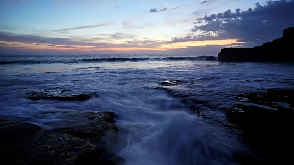 Dusk light on the water over the rock shelf below the clifftop at Tanah Lot