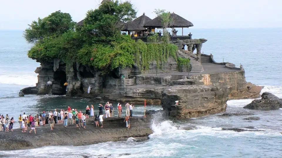Visitors crossing the exposed rock to the foot of the temple at low tide