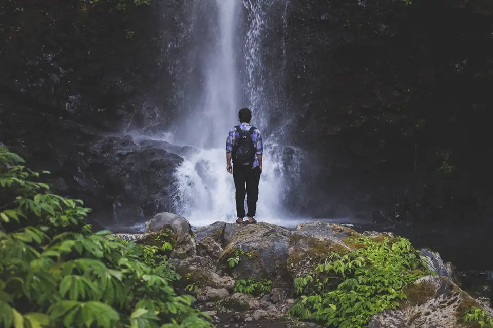 A visitor at the foot of a waterfall near Munduk