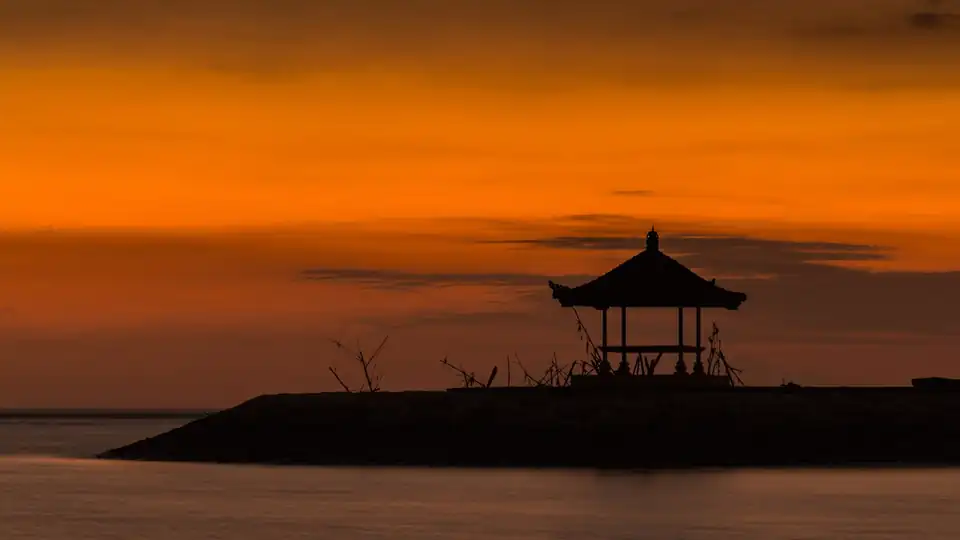 A pavilion silhouetted at sunrise over Sanur