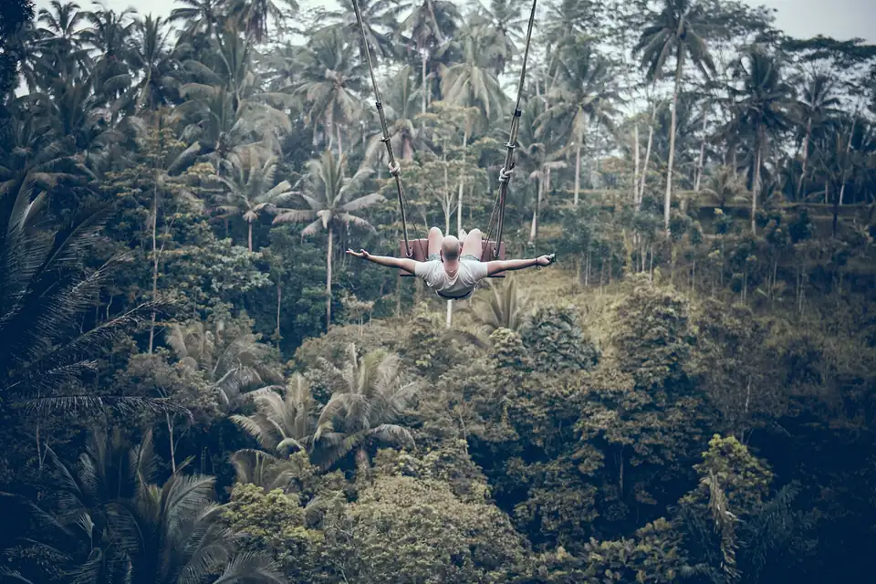 A rider on a jungle swing out over a forested valley in Bali