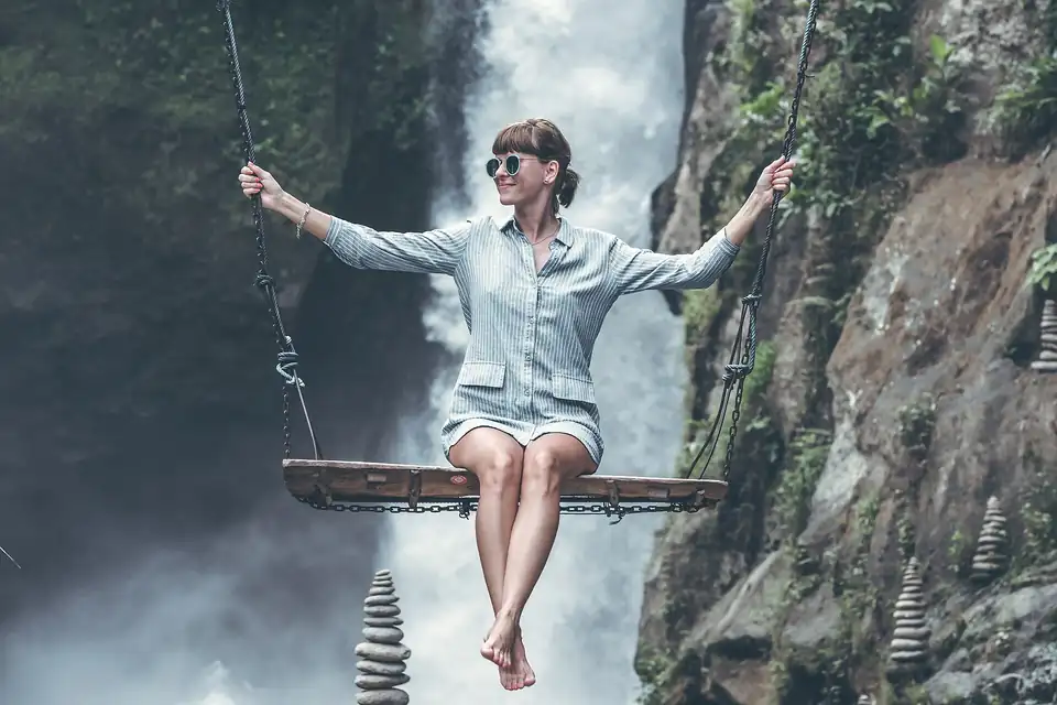 A rider on a rope swing beside a jungle waterfall in Bali