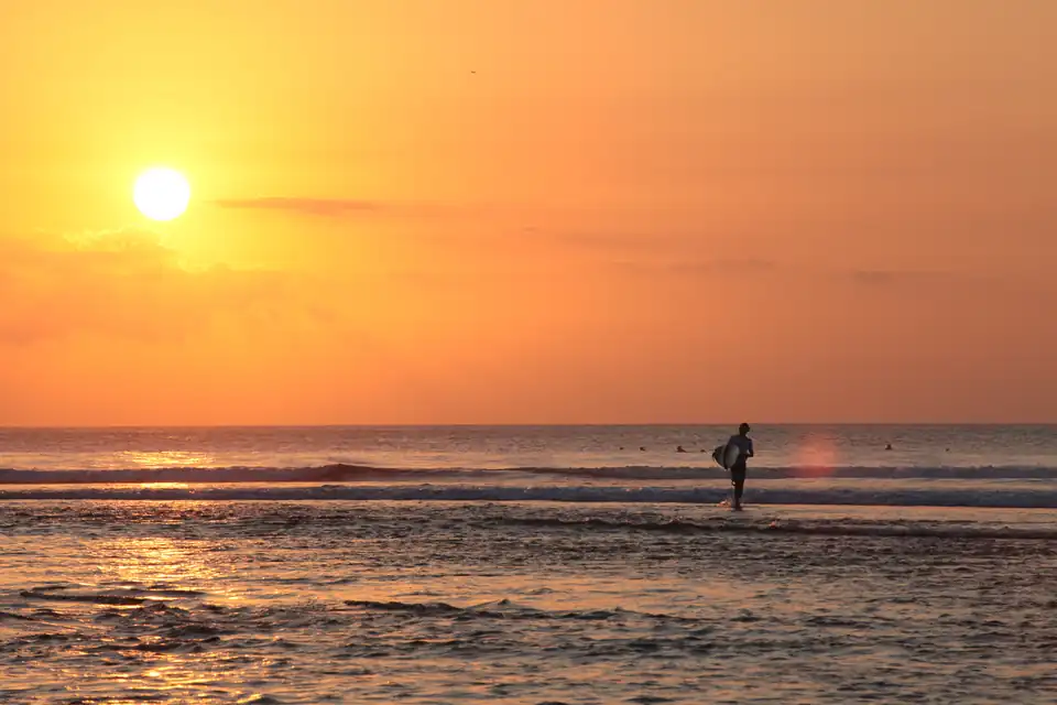 A surfer watching the waves at Balangan at sunset