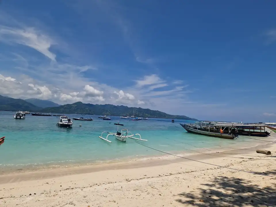 Outrigger boats pulled up on the sand with the mainland mountains across the strait