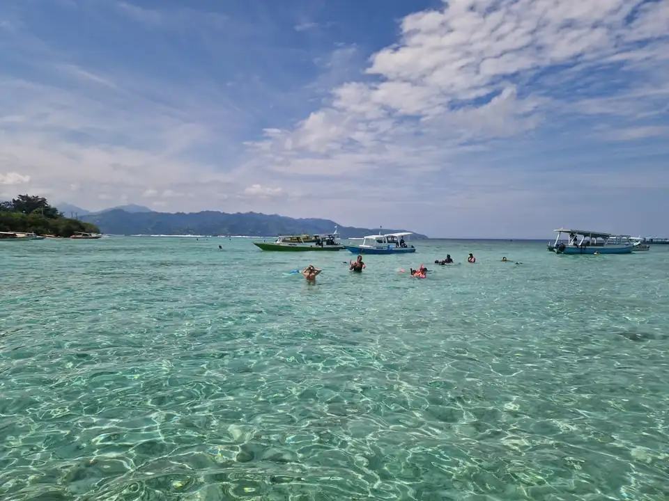 Snorkelling boats anchored over the shallow reef between the Gili Islands