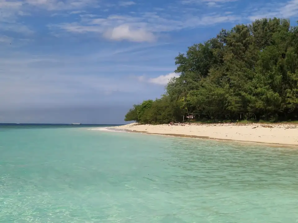 An empty stretch of white sand and shade trees on the Gili Islands