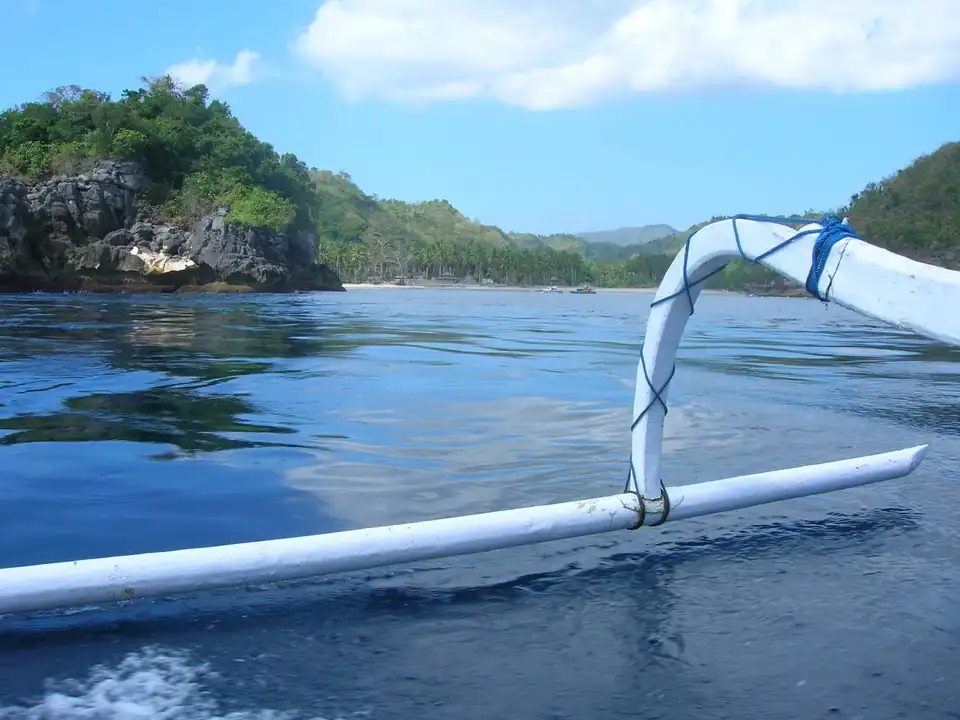 An outrigger boat moored over clear water at a Nusa Penida snorkelling site