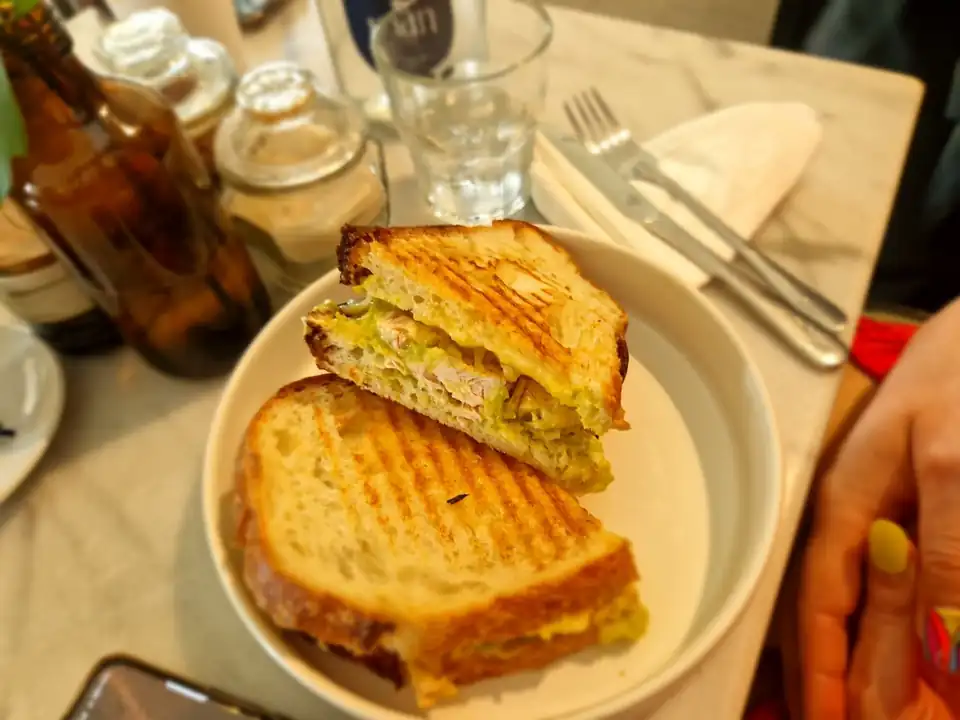A toasted sandwich and a glass of water on a marble cafe table in Bali