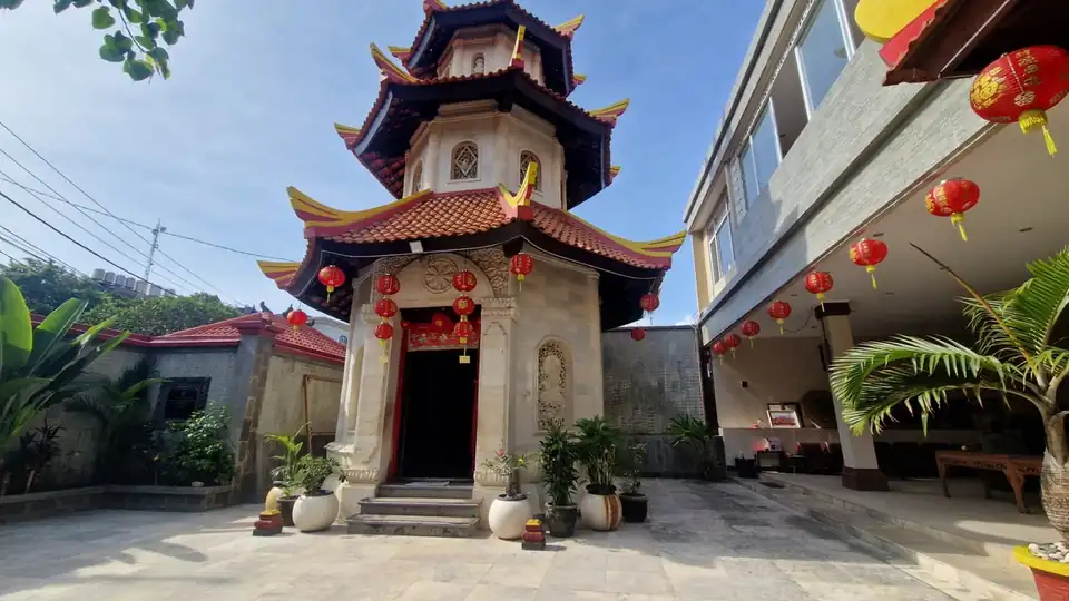 A Chinese temple in Bali with red lanterns strung along its eaves and a tiered pagoda in the courtyard