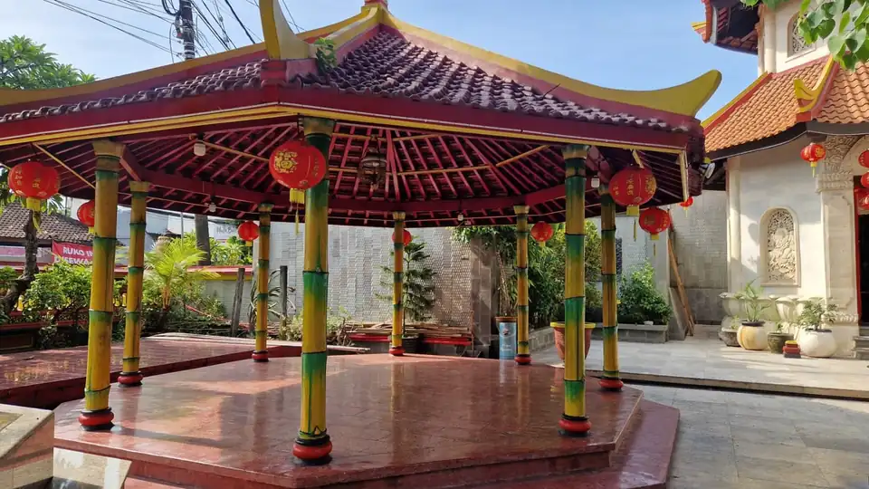 An open pavilion with painted bamboo columns and red lanterns in the courtyard of a Chinese temple in Bali