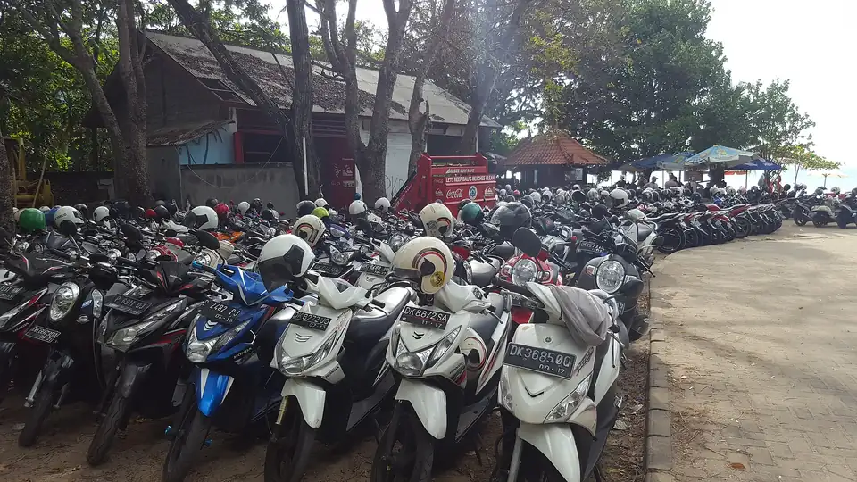 Rows of scooters with helmets parked in Kuta