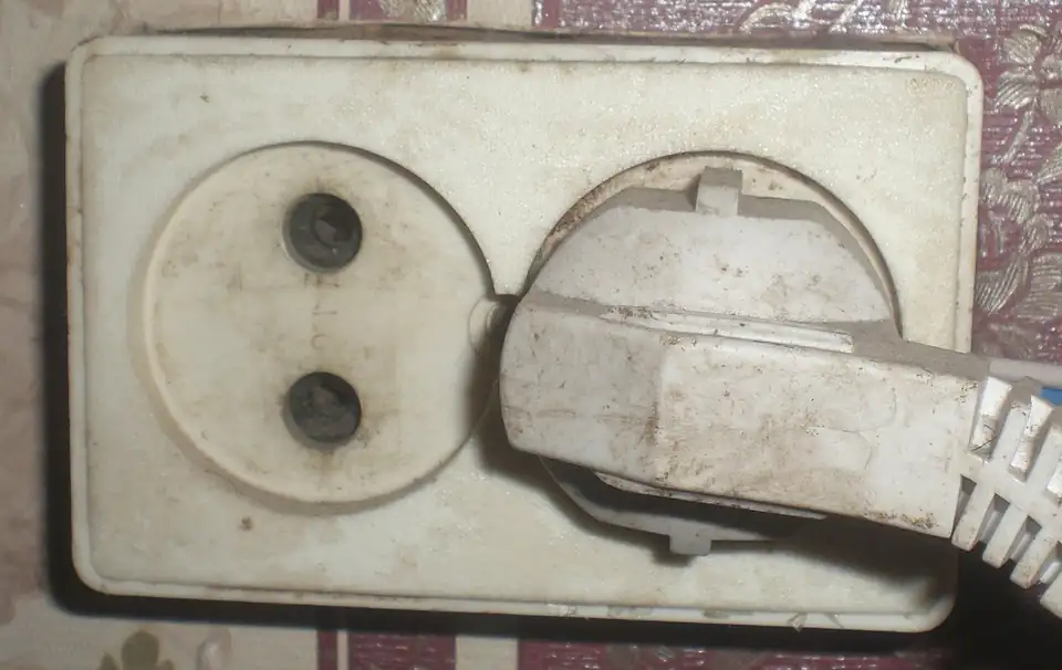 A Type F plug pushed into an older, unearthed Type C socket