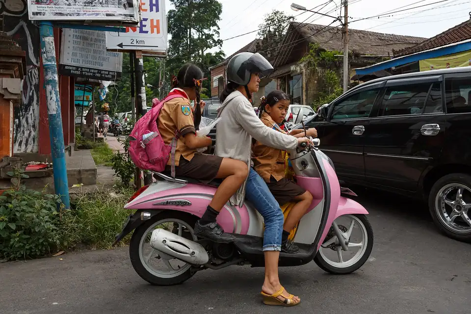 A mother taking her children to school by scooter on Jalan Raya Ubud
