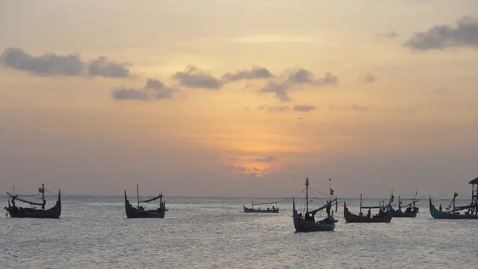 Fishing boats and beachfront seafood grills on the wide bay at Jimbaran