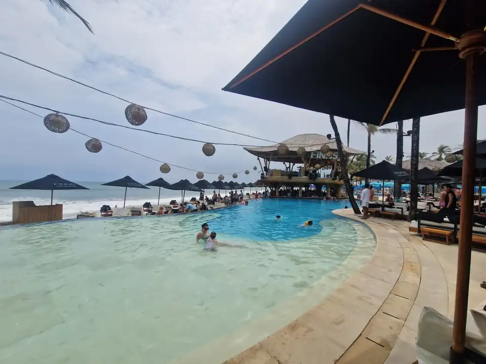 Loungers and lantern strings between the pool and the surf line at Canggu