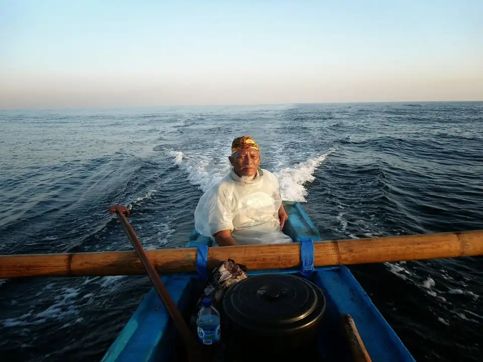 A fisherman working a traditional outrigger off Jimbaran