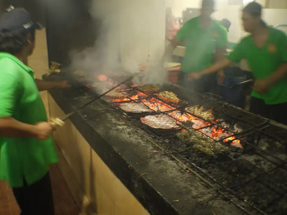 Fish grilling over coconut husks at a Jimbaran seafood warung