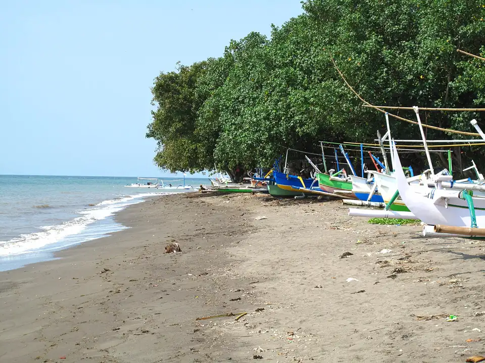 The dark-sand shoreline at Lovina with outrigger boats