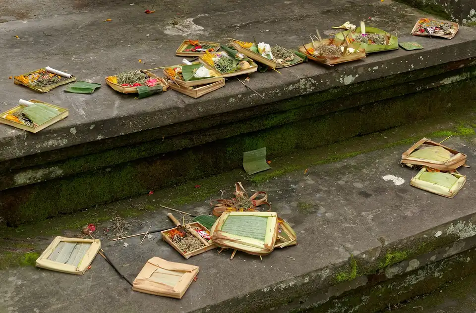 Canang sari offerings laid on the pavement of an Ubud street