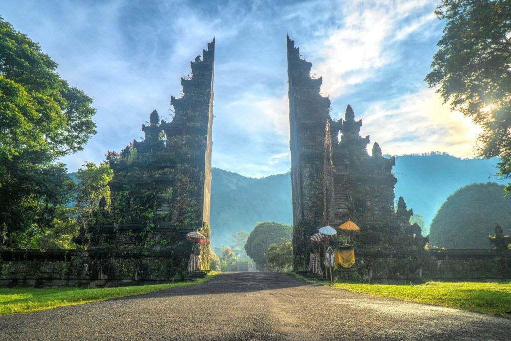 A traditional Balinese candi bentar split gate framing the misty Bedugul highlands at sunrise